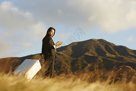 草原上拿着行李箱的女人图片