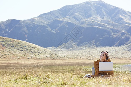 坐下在草地上工作的女人图片