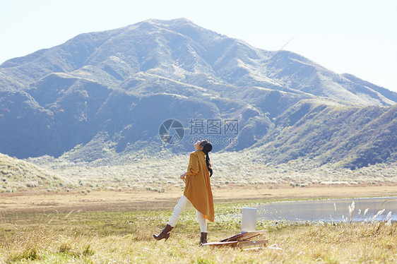 带着便携电脑旅行在草地上工作的女人图片