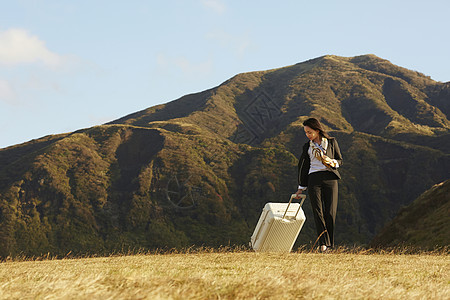 草原上拿着行李箱的职业女性图片