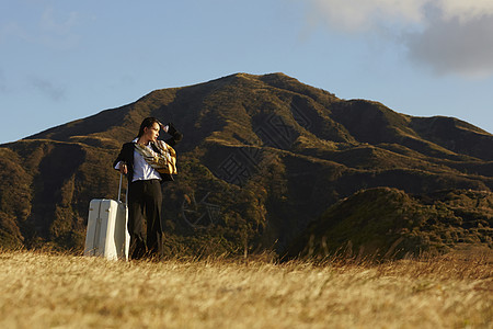 草原上拿着行李箱的职业女性图片
