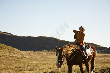 草原上骑马旅游的女人图片