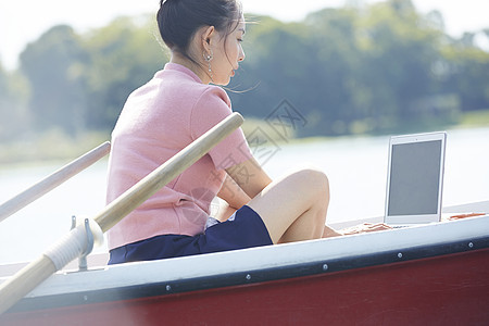 湖泊船上独自旅行的女人用电脑图片