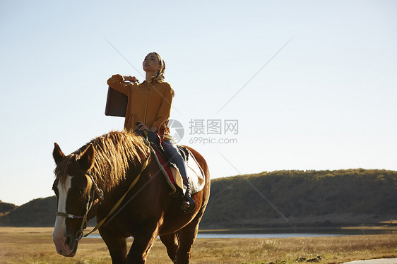 户外草原上骑马旅游的女人图片