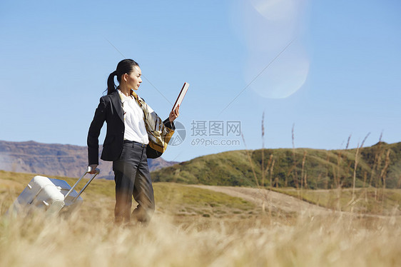 草原上的带着行李箱的女商人图片