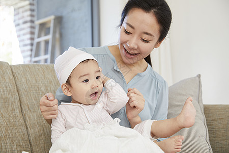 妈妈抱着婴儿在沙发上玩耍图片