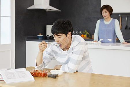 坐在餐桌上看书吃饭的男青年图片素材