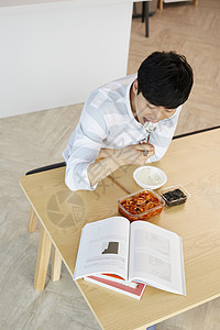 餐桌上看书吃饭的成年男子图片素材