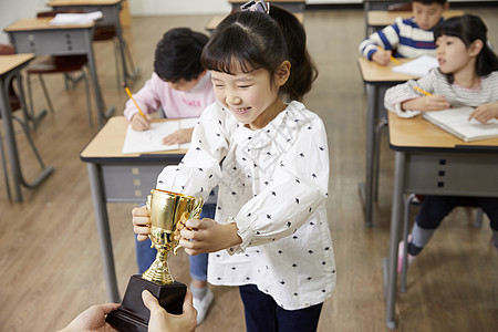 老师给小学生递奖杯图片