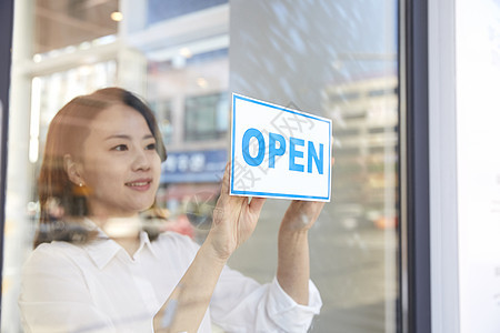 商店里贴上开门标志的年轻店员图片