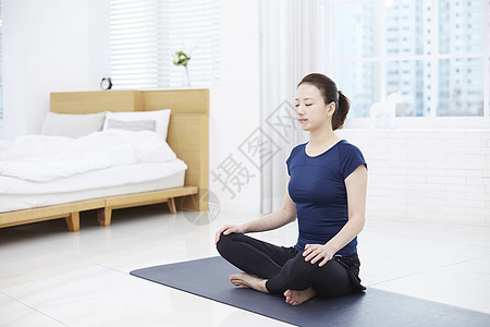 坐在瑜伽垫上闭眼冥想的年轻女子图片
