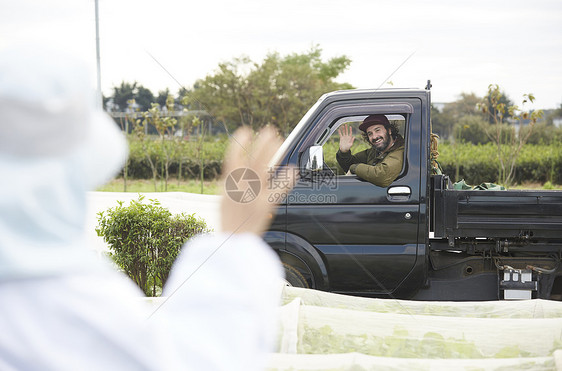 友谊空白部分领域外国人驾驶一辆卡车与一名妇女在农业工作图片