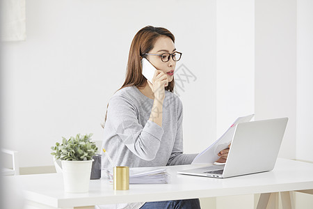 年轻女人在用电脑办公打电话图片