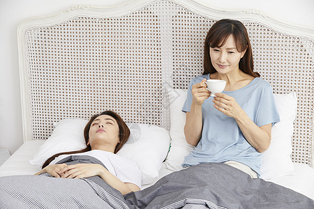 妈妈和女儿一起生活睡醒在床上喝茶图片