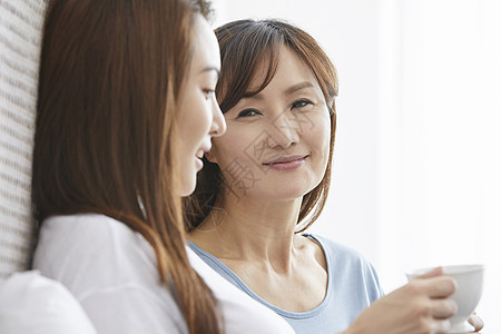 妈妈和女儿一起生活在床上喝茶聊天图片