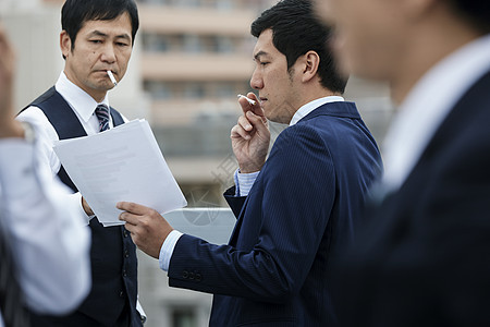 户外吸烟谈项目的男士图片