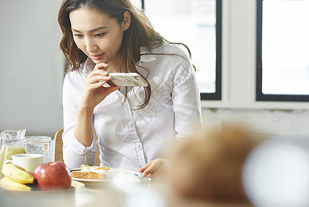 早晨室内女强人拍摄自制早餐的职业女图片