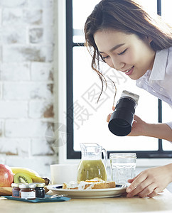 用相机拍摄自制早餐的职业女性图片