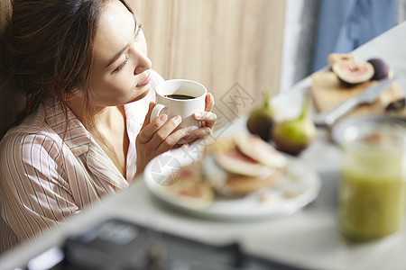 穿着睡衣厨房里喝咖啡的女青年图片