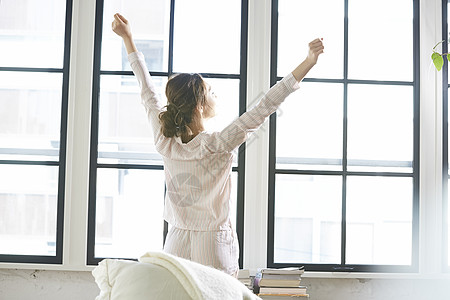 站在窗边伸懒腰的女子背影图片素材