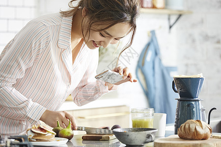 厨房制作料理拿着手机拍摄的女青年图片