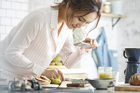 厨房制作料理拿着手机拍摄的女子图片