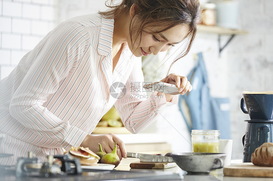 厨房制作料理拿着手机拍摄的女子图片