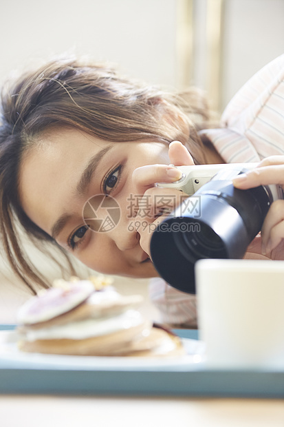 拿着相机拍食物照片的女青年图片