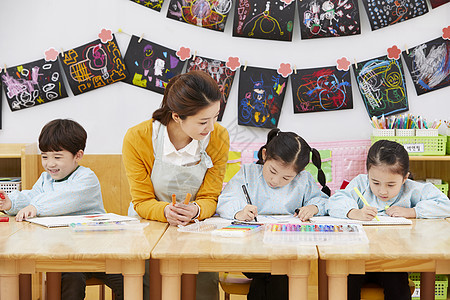 幼儿园的老师在带着学生们画画图片