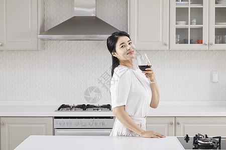 厨房里拿着红酒微笑的青年女子图片