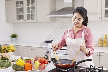 厨房里烹调食物的年轻女子图片