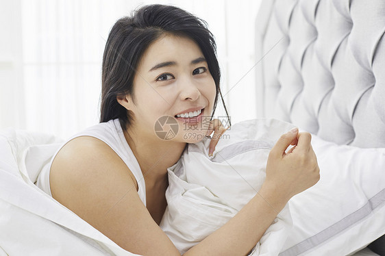 床上微笑的成年女子图片