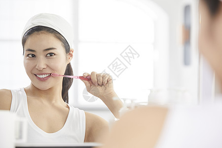 镜子前拿着牙膏洗漱的女青年图片