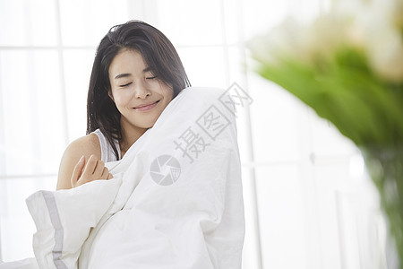 盖着被子的人抱着被子微笑的青年女性背景