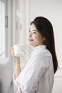 居家拿着水杯微笑的女青年图片