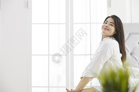 坐在床上微笑的年轻女子图片