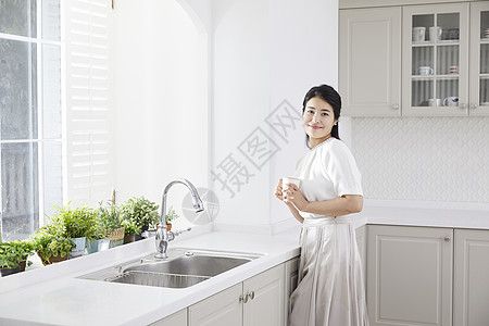 厨房里拿着水杯微笑的年轻女子图片