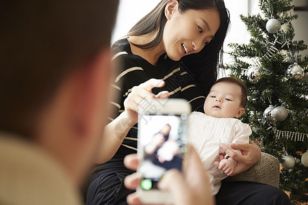 用智能手机给宝宝拍照的一家人图片