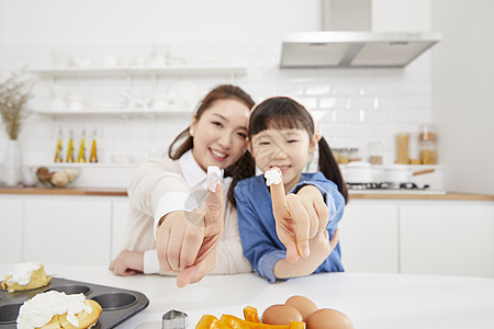 厨房里食指沾上奶油的母女图片