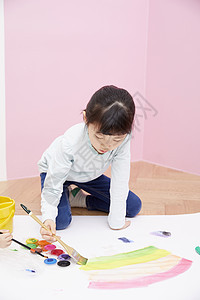 拿着刷子在画纸上涂鸦的小女孩图片