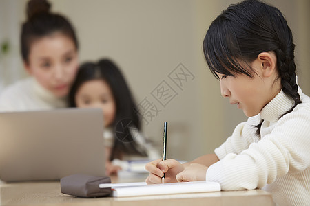 女孩写作业与母亲的孩子工作在客厅图片