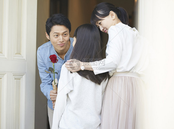 爸爸拿着一只花送给母亲和女儿图片