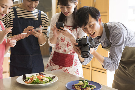 户内厨房拍摄食物的男女图片