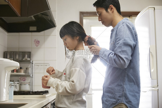 单身父亲为女儿扎辫子准备早餐图片