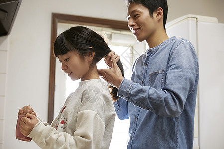 单身父亲为女儿扎辫子图片素材