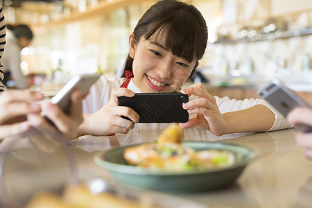 女子用手机拍照食物图片