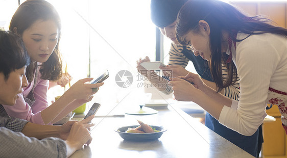 用手机拍摄食物的男女图片