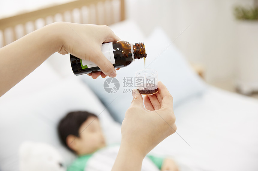 妈妈照顾生病在床的男孩吃药图片
