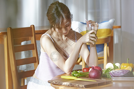 居家喝果汁关注饮食健康的年轻女子图片