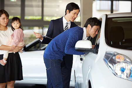 思考日本人父亲考虑汽车经销商购买的家庭汽车4s店内的销售员与顾客图片
